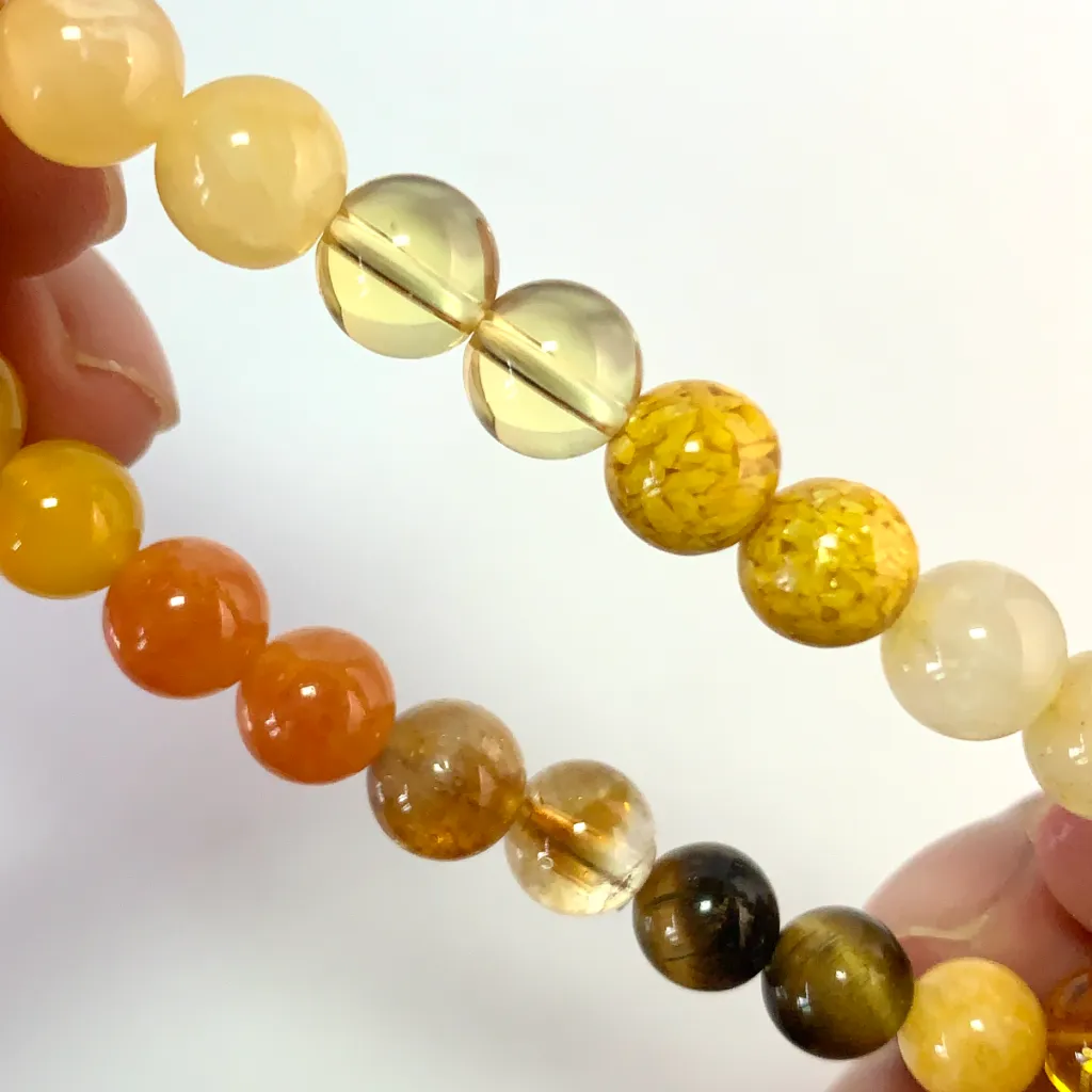 Detail of the Earth Element Bracelet: faceted yellow tower crystal, gold tiger eye band, and golden rutilated quartz catching the light