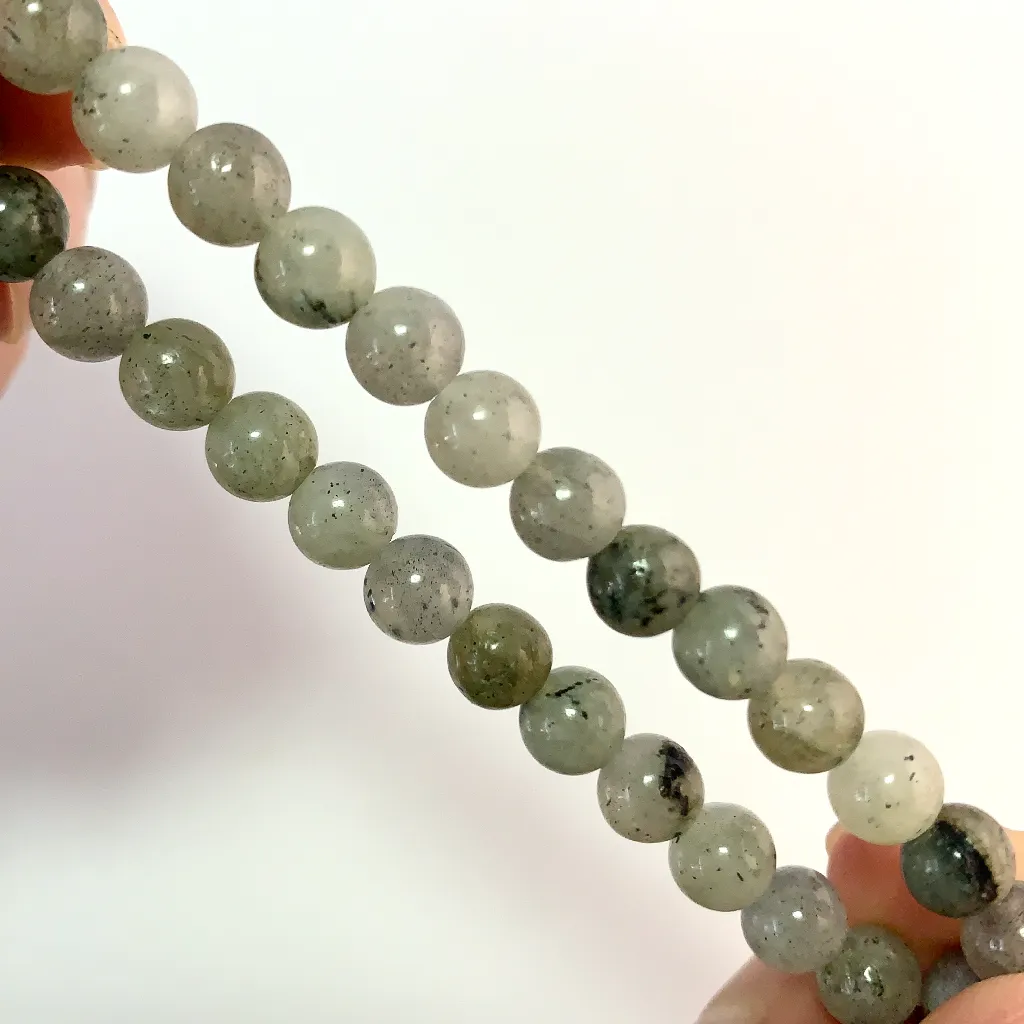 Close-up of White Flash Stone Bracelet beads showing natural gray-green tones and dark mineral flecks